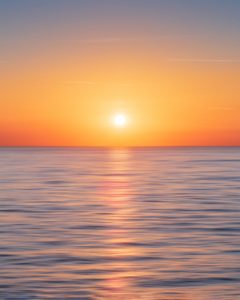calm water with sun and orange sky